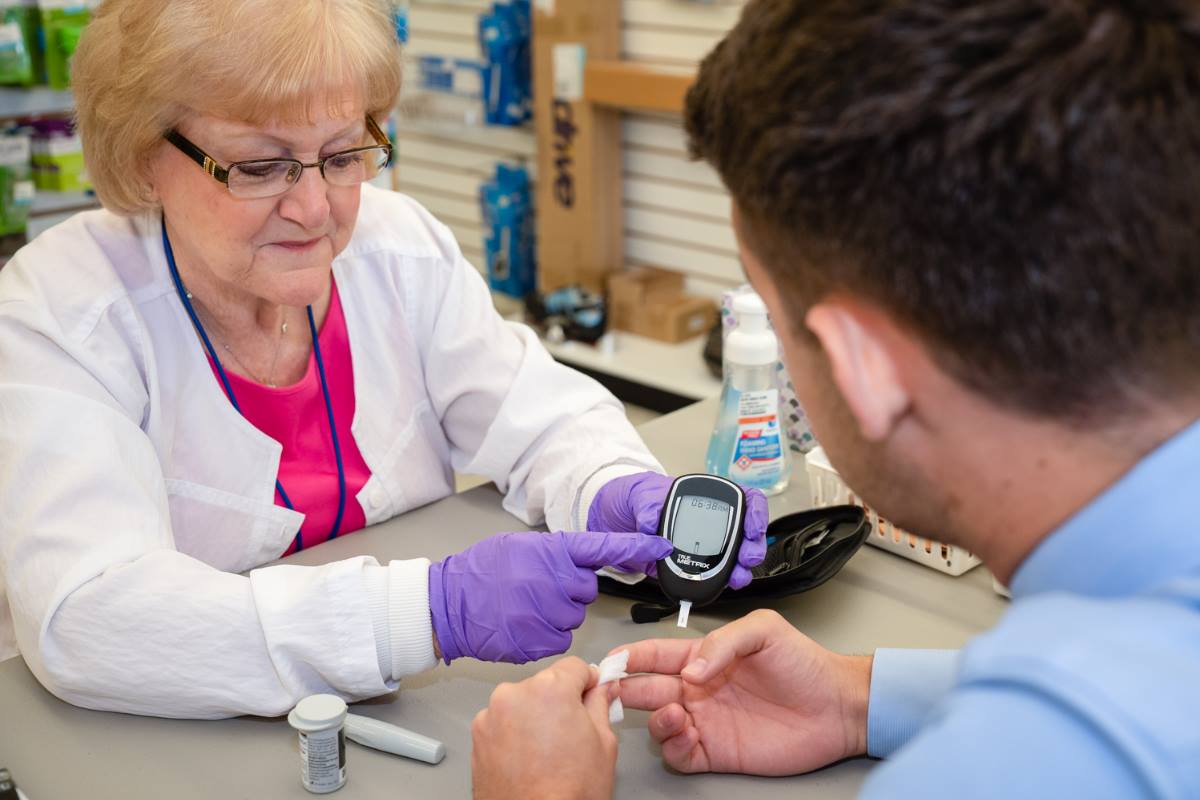 Nurse diabetes care to patient using glucose meter