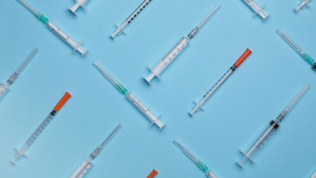 Disposable syringes with needles on light blue background, flat lay