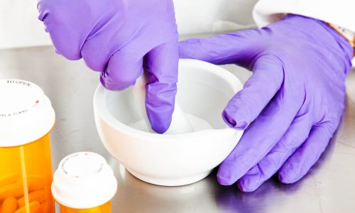 Closeup view of a pharmacist's hands, using a mortar and pestle.